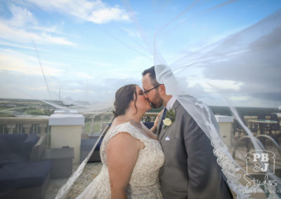 Bride and groom with bride's veil flying in the wind