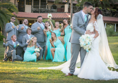 Bride and groom kissing with wedding party background