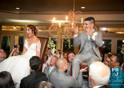 Bride and groom carried on chairs