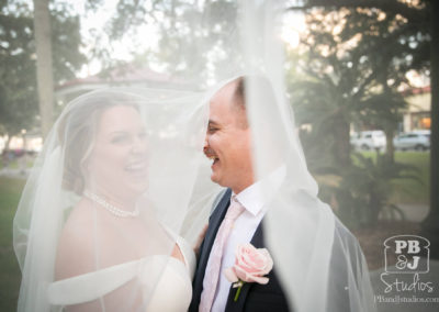 Kate and Steven laughing with wedding veil flying in the wind