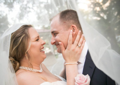 Kate and Steven laughing with wedding veil flying in the wind