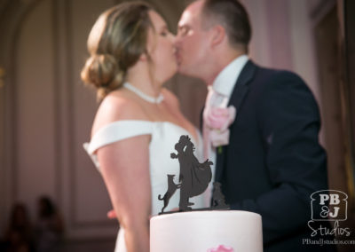 Kate and Steven kissing behind wedding cake